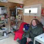 Frau aus dem Tauschbox Team die freundlich lächelnd auf einem Stuhl in der Tauschbox sitzt