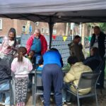 Gemischte Gruppe von Menschen unter einem Pavillion beim Nachbarschaftsfest